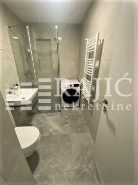 Modern bathroom with a walk-in shower, washbasin, and washing machine. - image 5