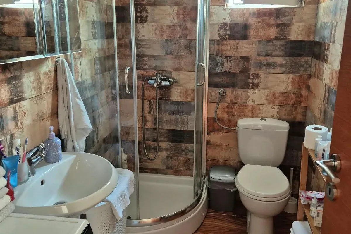 Compact bathroom with a shower cabin, sink, and toilet.