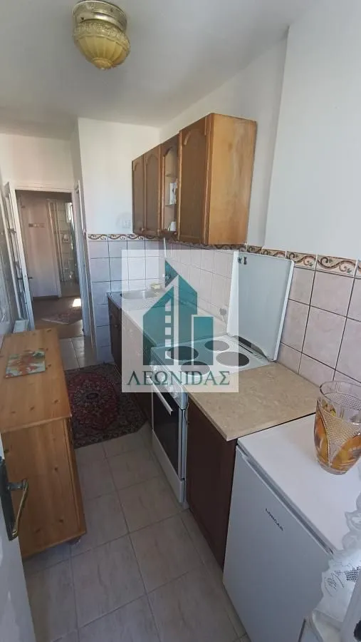 Small kitchen with wooden cabinets, a stove, and a refrigerator.