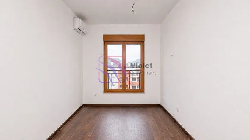 Empty room with wooden flooring, air conditioning unit, and a window.