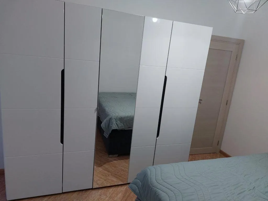 Bedroom with a large white wardrobe featuring a mirror and a bed.