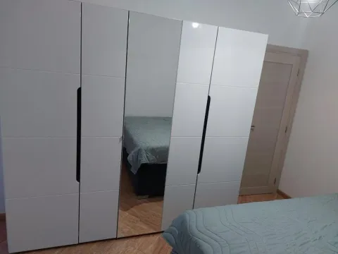 Bedroom with a large white wardrobe featuring a mirror and a bed. - image 19