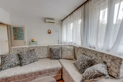 Living room with a large corner sofa and windows covered with white curtains. - image 2