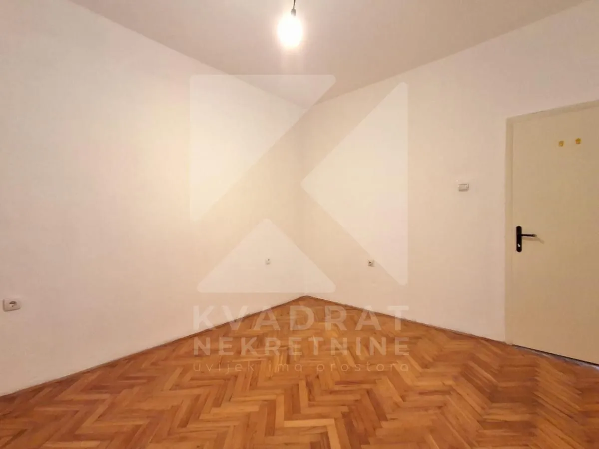 Empty room with parquet flooring and white walls.