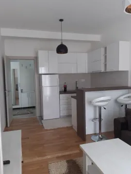 Moderna kuhinja sa bijelim elementima i šankom u sklopu dnevnog boravka. - image 2
