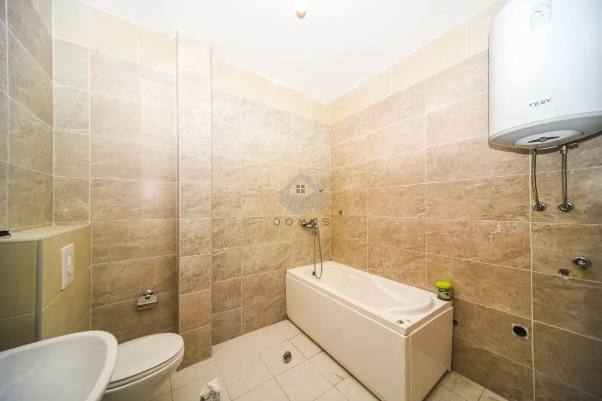 Bathroom equipped with ceramic tiles, bathtub, toilet and water heater.