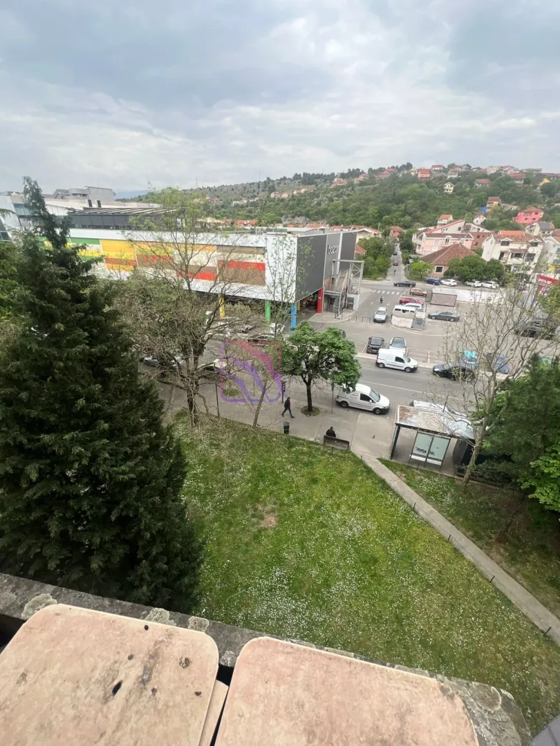 Pogled sa terase na okolne zgrade, parking i zelenu površinu.