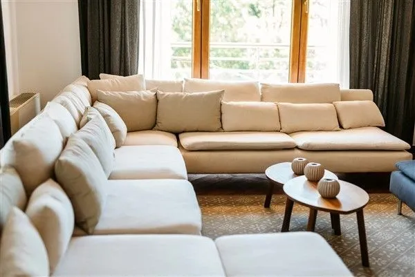 A spacious beige sectional sofa in a living room with wooden coffee tables.