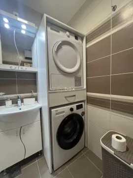 Bathroom with a sink, mirror, and stacked washing and drying machines. - image 17
