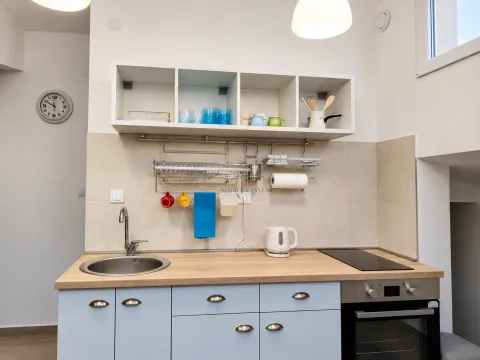 Compact kitchen with sink, built-in cooktop and upper cabinets. - image 5