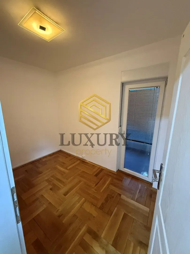 Empty room with parquet flooring and balcony access.