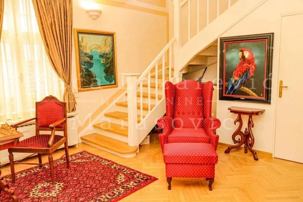 Dnevni boravak sa stepeništem i crvenim foteljama.