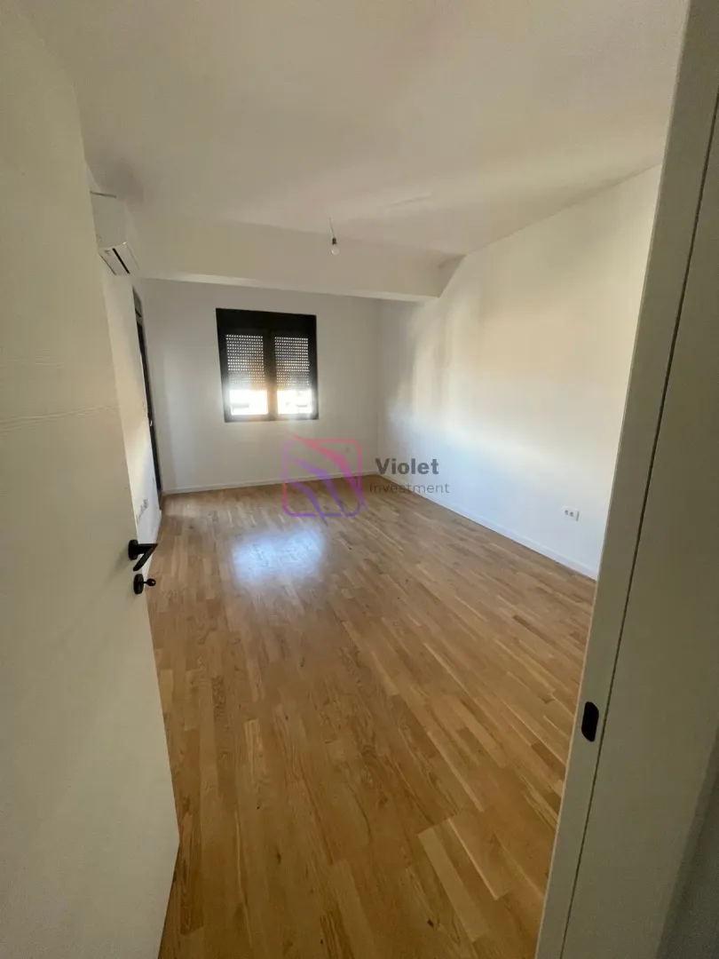 Empty room with wooden flooring and a window.