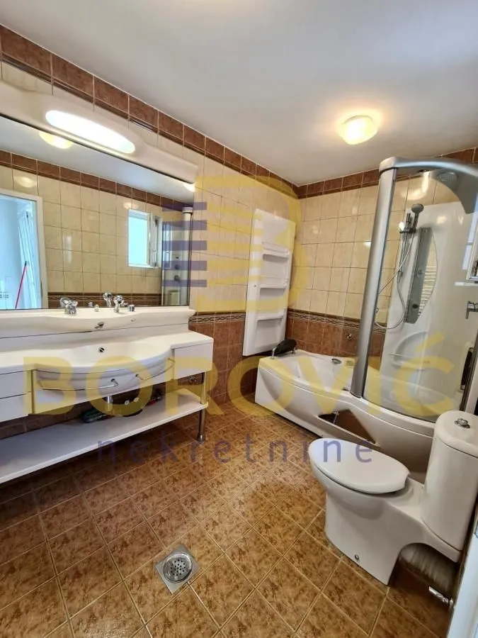 Kupatilo obloženo keramičkim pločicama sa dvostrukim umivaonikom, kadom i tuš kabinom.