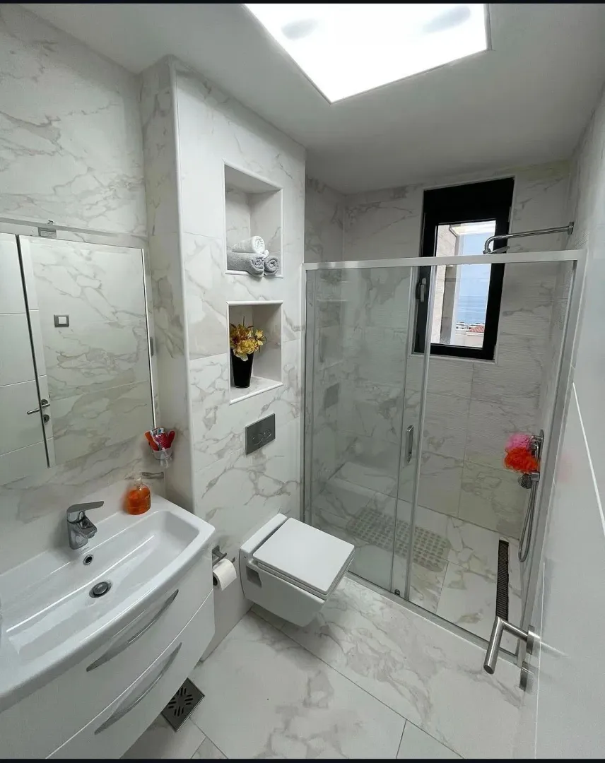 Modern bathroom with a walk-in shower, washbasin, and built-in fixtures.