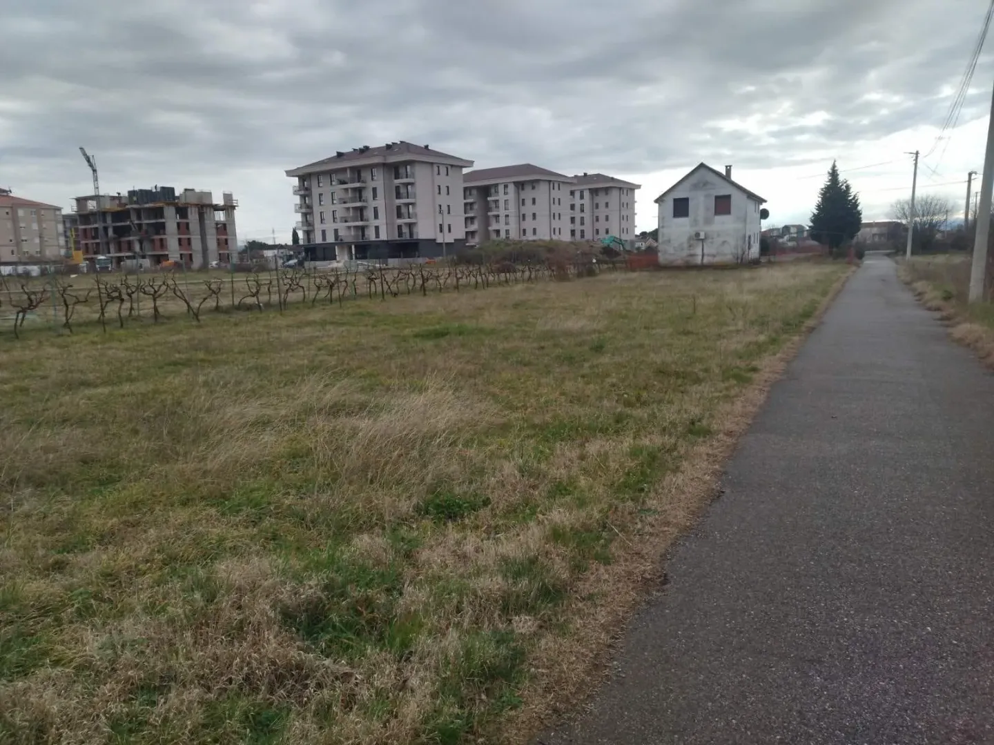 Pogled na plac sa putem i okolnim zgradama u pozadini.