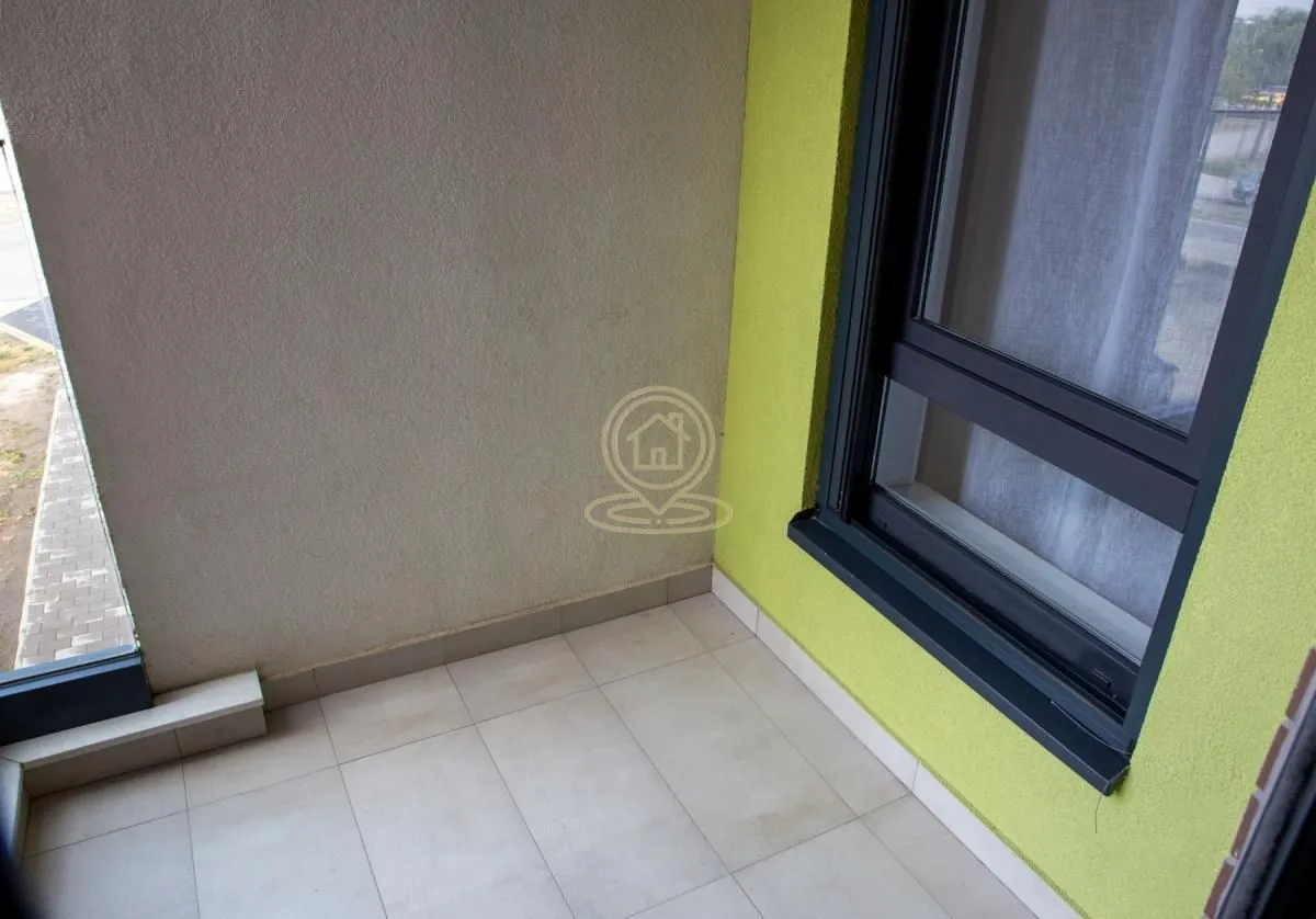 Manji popločani balkon sa prozorom i svetlim zidovima.