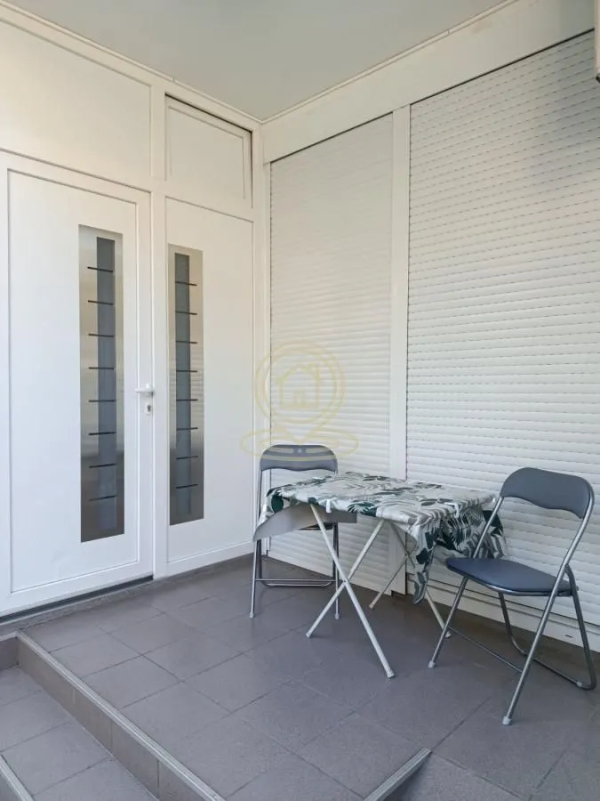 Covered terrace with a table and two chairs.
