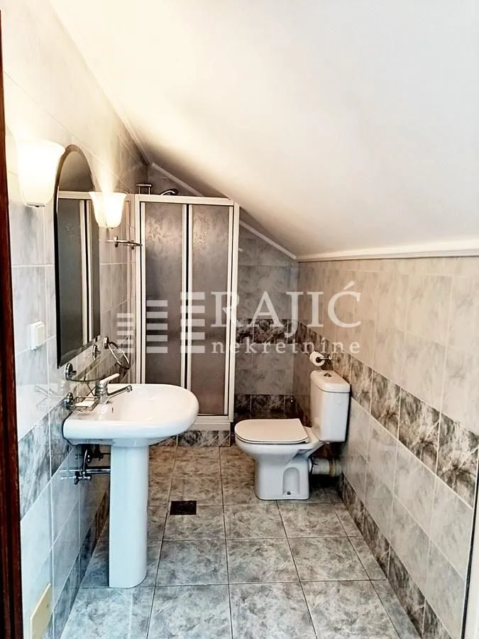 Smaller bathroom with a sink, shower cabin, and toilet in the attic.