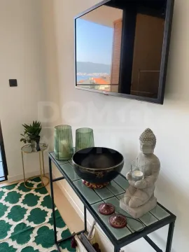 Detalj enterijera sa konzolnim stolom i televizorom na zidu. - image 3