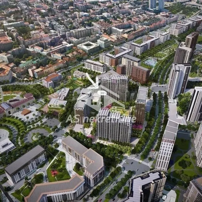 Prikaz naselja iz vazduha sa modernim zgradama i uređenim zelenim površinama.