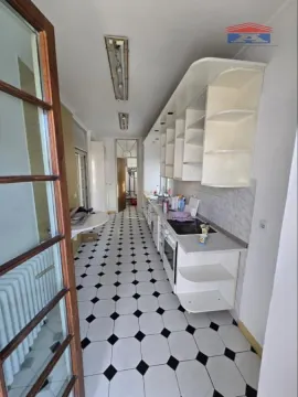 Long kitchen with white cabinetry and black and white ceramic floor tiles. - image 7