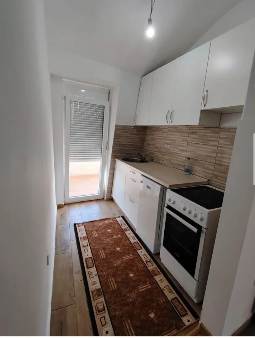 Small kitchen with white units and access to the terrace.