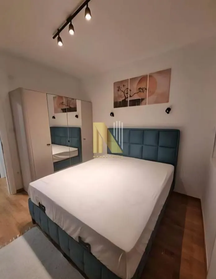 Moderna spavaća soba sa bračnim krevetom, plakarom i dekorativnim osvetljenjem.