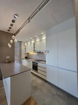 Modern white kitchen with a breakfast bar and built-in appliances. - image 9