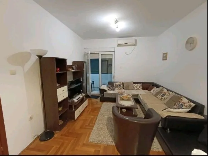 Dnevna soba sa ugaonom garniturom, drvenim namještajem i parketom.