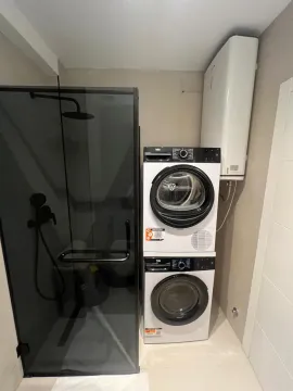 Bathroom with a shower cabin and stacked washing and drying machines. - image 2