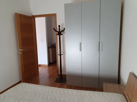 Spavaća soba sa sivim ormarom, drvenim podom i krevetom sa dušekom. - image 6