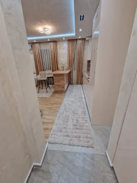 A bright kitchen with a dining table and bar stools viewed from the hallway. - image 2