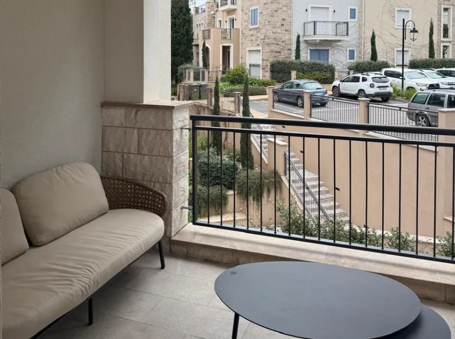 Natkriveni balkon sa garniturom za sedenje i pogledom na naselje.