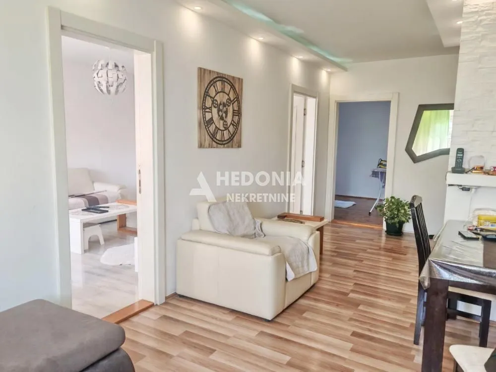 Pogled na dnevnu sobu i hodnik sa garniturom i trpezarijskim stolom.