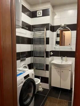 Small bathroom with black and white tiles, a sink, and a washing machine. - image 6