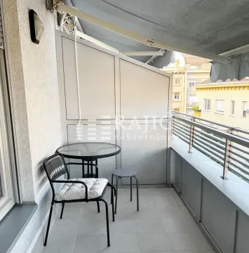 Covered balcony area with a small table and chairs. - image 6