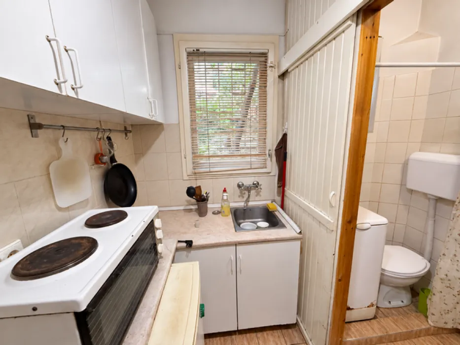 Small kitchen with a stove, sink, and an open passage leading to the bathroom.