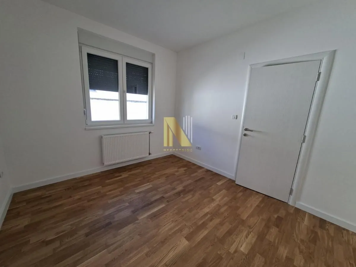Empty room with hardwood flooring, white walls, and a window.
