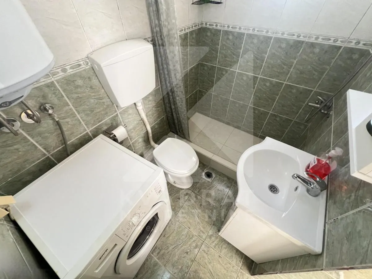 Manje kupatilo sa tuš kabinom, umivaonikom, WC šoljom i veš mašinom.