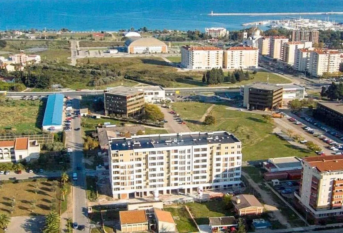 Aerial view of the residential building and the surrounding neighborhood with a sea view.
