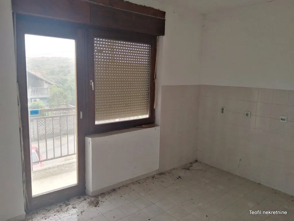 Prazna prostorija sa keramičkim pločicama i balkonskim vratima.