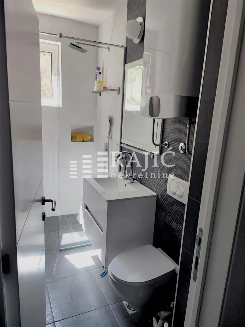 Modern bathroom with a walk-in shower, washbasin, and toilet.
