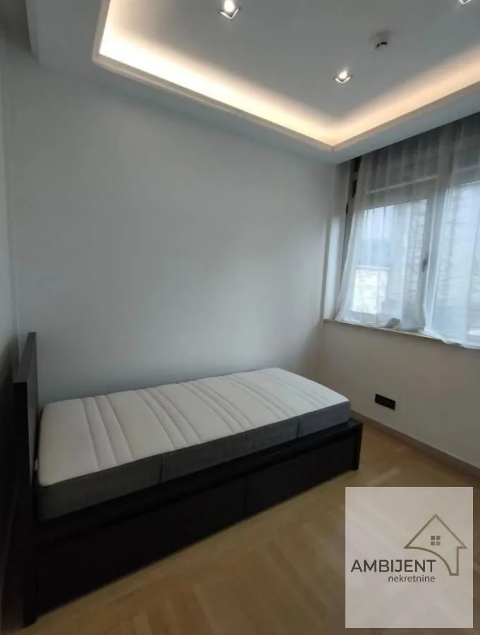 Small bedroom with a bed and a dropped ceiling with lighting.