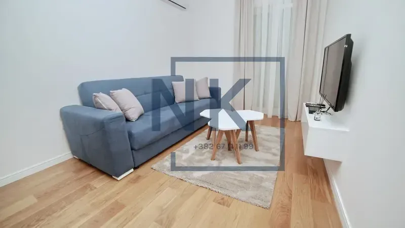 Dnevna soba sa plavom sofom, stočićem i televizorom.