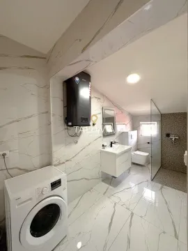 Modern bathroom with a walk-in shower, washbasin, and washing machine. - image 17