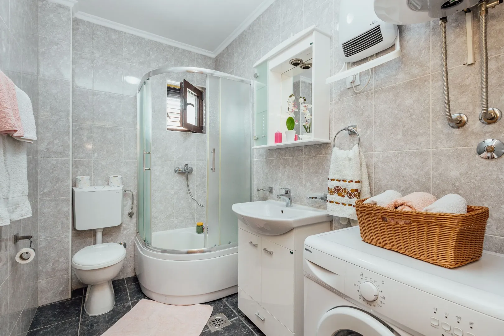 Bathroom equipped with a shower cabin, washbasin, toilet, and washing machine.