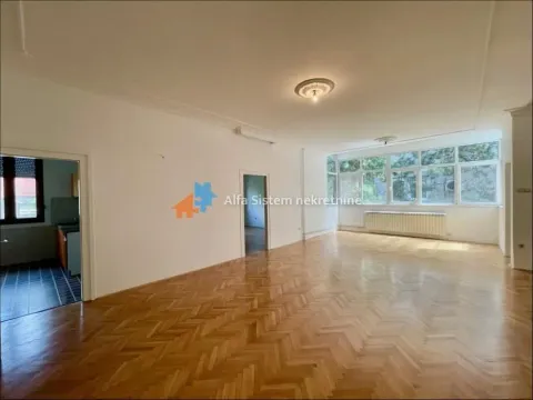 Spacious empty living room with parquet flooring and large windows. - image 2