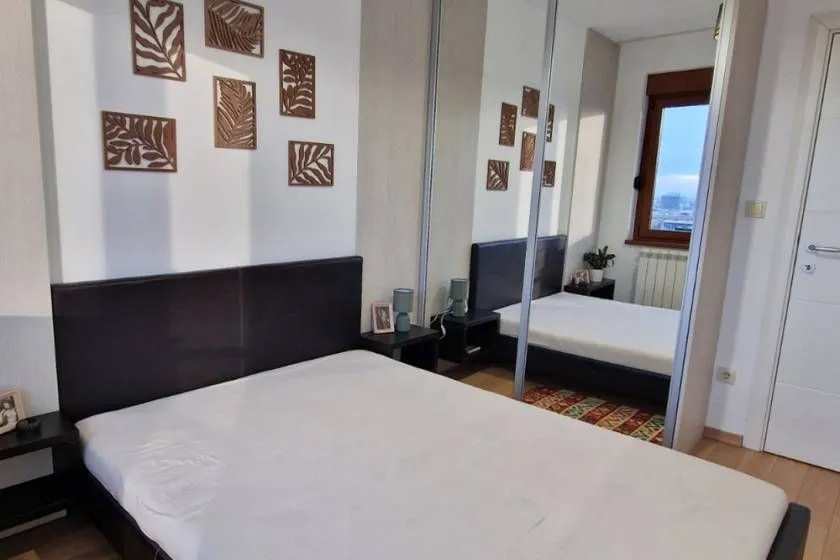 Bedroom with a double bed, bedside tables, and a large built-in wardrobe with a mirror.