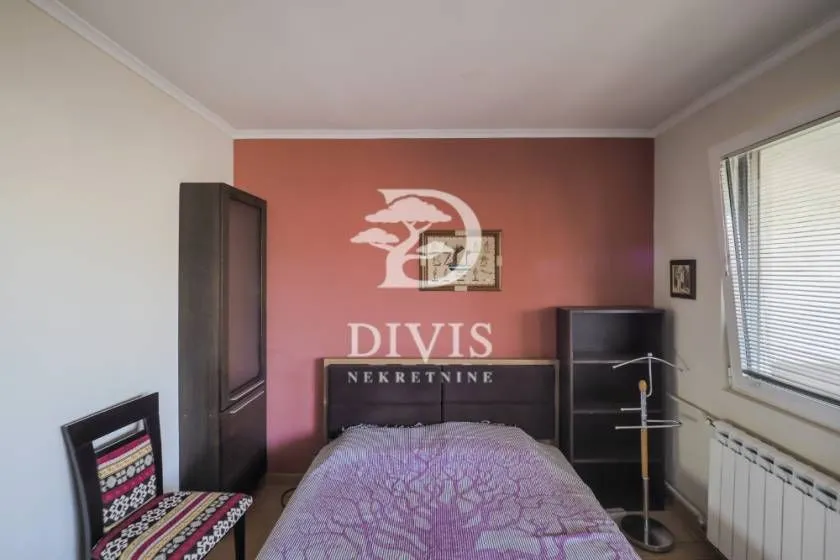 Nameštena spavaća soba sa bračnim krevetom, ormarom i prozorom.